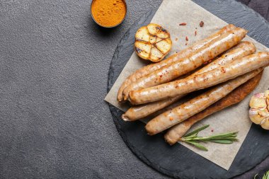 Lezzetli ızgara sosis ve koyu arkaplanda sarımsak tabağı.