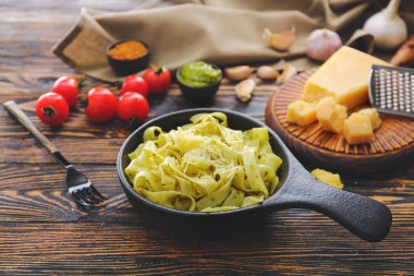 Koyu ahşap masada lezzetli makarna ve pesto soslu tava.