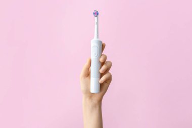 Arka planda elektrikli diş fırçası olan el