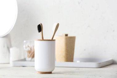 Banyodaki masada tahta diş fırçaları olan bir tutucu.