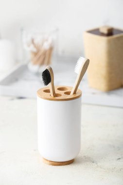 Banyodaki masada tahta diş fırçaları olan bir tutucu.