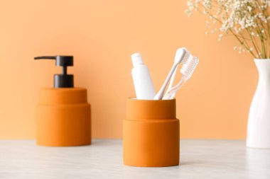 Banyodaki masada diş fırçası ve diş macunu olan bir tutucu.