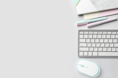 Işık arkaplanındaki bilgisayar klavyesi, fare ve kırtasiye malzemesi