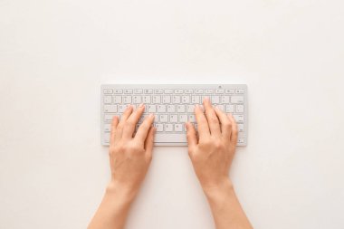 Beyaz arkaplanda bilgisayar klavyesi olan kadın elleri