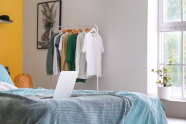 Rahat yatak odasının içinde, yatağın üstünde modern bir laptop.