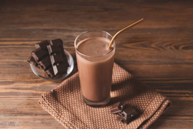 Ahşap arka planda bir bardak aromatik çikolatalı süt.