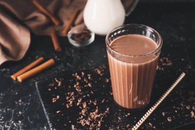Koyu arkaplanda bir bardak aromalı çikolatalı süt.