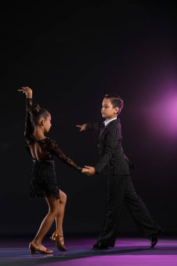 Tatlı küçük çocuklar karanlık arka planda dans ediyor.