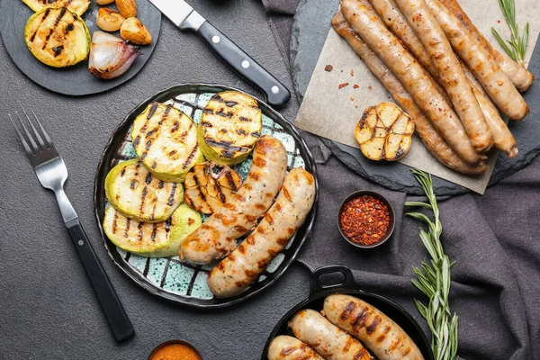 Lezzetli ızgara sosis ve koyu arkaplanda sebze tabağı.