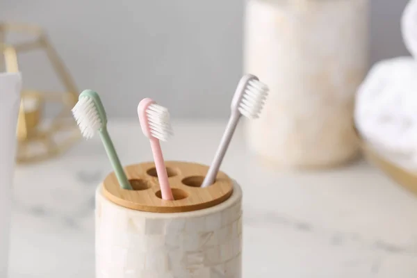 Holder with toothbrushes on table in bathroom