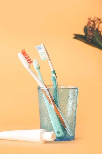Holder with toothbrushes and toothpaste on color background