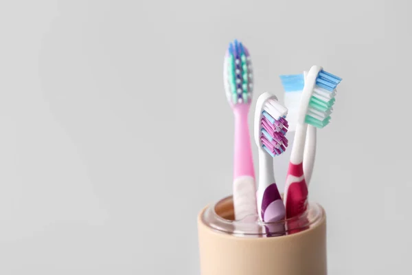 Holder with toothbrushes on light background