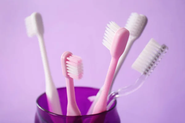 Holder with toothbrushes on color background