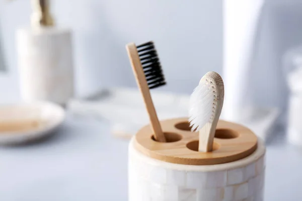 Holder with wooden toothbrushes on table in bathroom