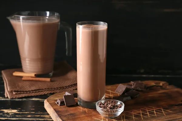 暗い背景においしいチョコレートミルクのガラスと木製のボード — ストック写真