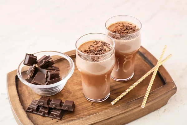 Wooden board with glasses of tasty chocolate milk on board