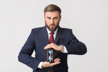 Hafif arka planda kum saati olan bir iş adamı