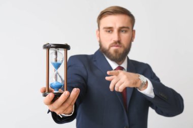 Hafif arka planda kum saati olan bir iş adamı