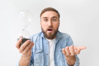 Şok olmuş genç bir adam, arka planda kum saatiyle