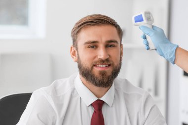 Ofisteki insanın ateşini ölçüyorum. Coronavirüs salgını