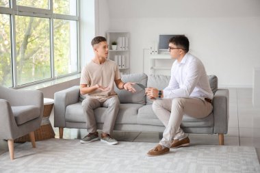 Ofiste genç bir çocukla çalışan psikolog.