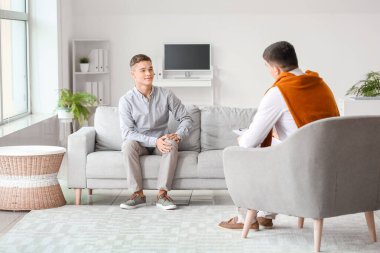 Ofiste genç bir çocukla çalışan psikolog.