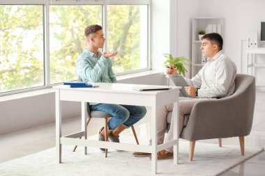 Ofiste genç bir çocukla çalışan psikolog.