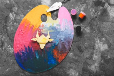 Koyu arkaplanda origami boğası olan paleti boya