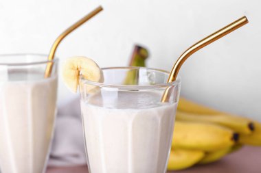 Glass of tasty banana smoothie on table, closeup