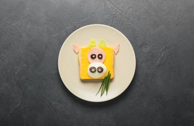 Koyu arkaplanda boğa şeklinde lezzetli bir sandviç tabağı.