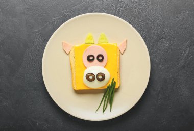 Koyu arkaplanda boğa şeklinde lezzetli bir sandviç tabağı.