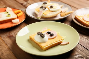 Tahta zemin üzerinde boğa şeklinde lezzetli sandviçler olan tabaklar.