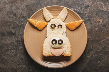 Koyu arkaplanda boğa şeklinde lezzetli bir sandviç tabağı.