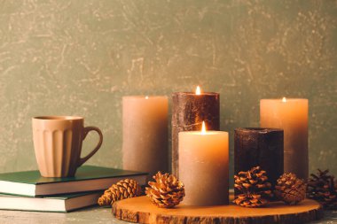 Güzel aroma mumları, kitaplar ve gri arka planda bir fincan kahve.