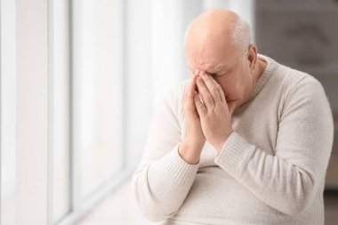 Kliniğin penceresinin yanındaki üzgün yaşlı adam. Prostat kanseri farkındalığı