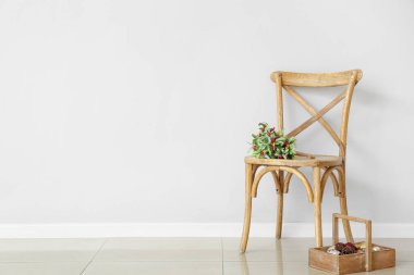 Aydınlık duvara yaslanmış bir sandalyede ökseotu dalı