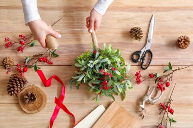 Masanın üzerinde ökseotu dallarıyla kompozisyon yapan kadın