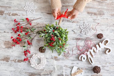 Masanın üzerinde ökseotu dallarıyla kompozisyon yapan kadın