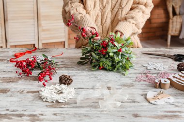 Masanın üzerinde ökseotu dallarıyla kompozisyon yapan kadın