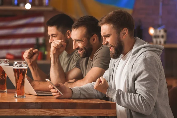 Bardaki spor bahislerini kazandıktan sonra mutlu adamlar.