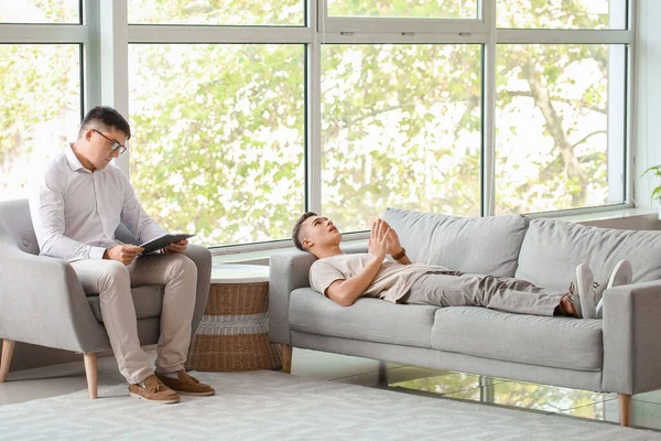 Ofiste genç bir çocukla çalışan psikolog.