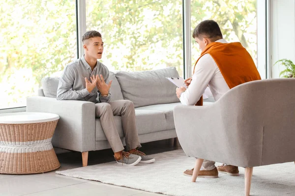 Ofiste genç bir çocukla çalışan psikolog.