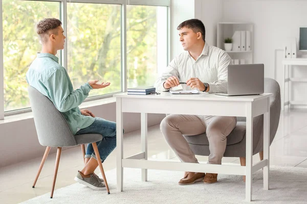 Ofiste genç bir çocukla çalışan psikolog.