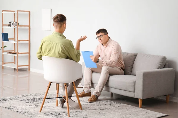 Ofiste genç bir çocukla çalışan psikolog.