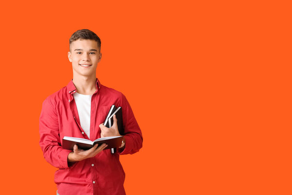 Teenage boy with books on color background