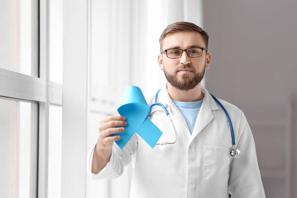 Доктор с голубой лентой в клинике. Концепция информирования о раке предстательной железы