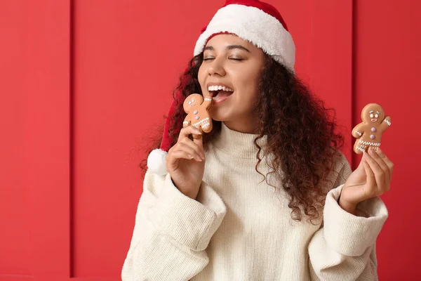 Hermosa Joven Santa Sombrero Comiendo Sabrosas Galletas Jengibre Fondo Color —  Fotos de Stock