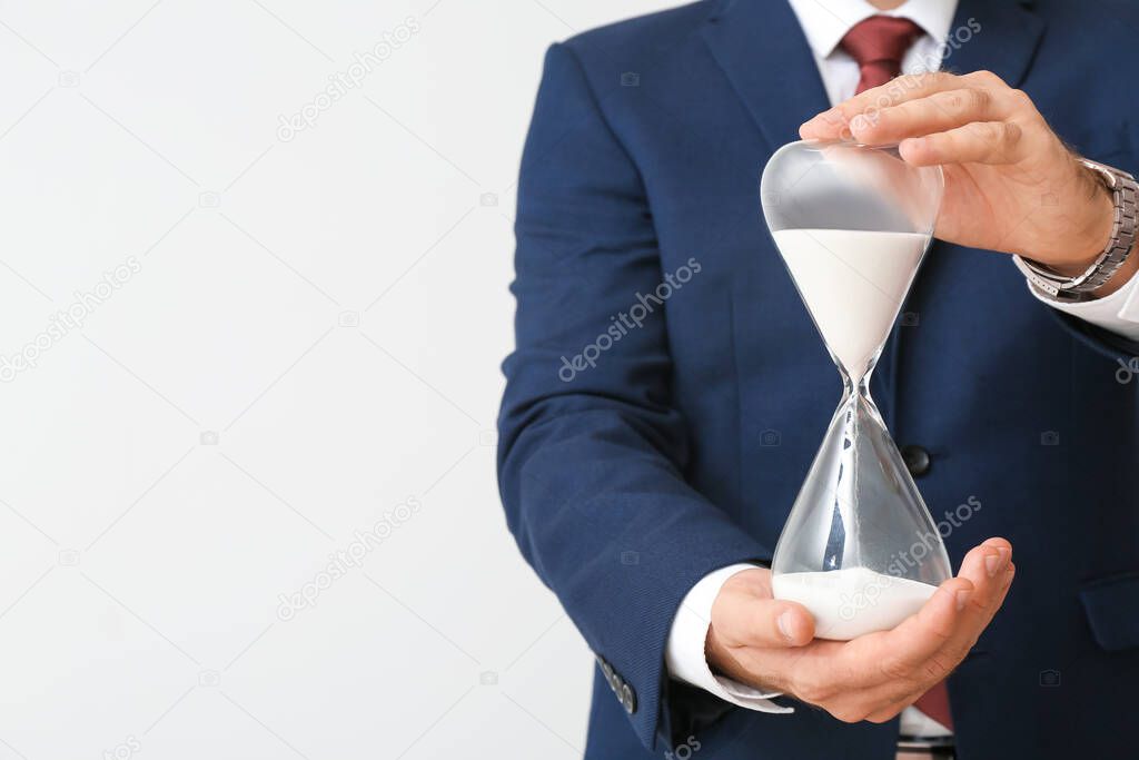 Businessman with hourglass on light background, closeup