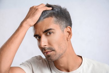 Açık arkaplanda kır saçlı bir adam.