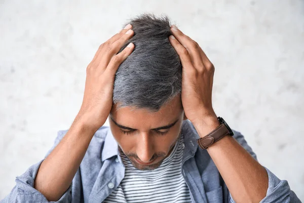 Stressed man with graying hair on light background